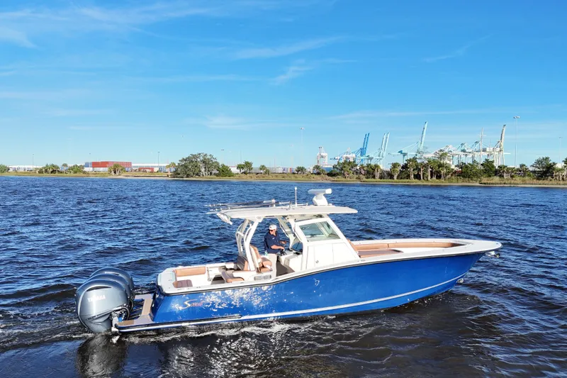 Slide: The Image of 2017 Scout 350 LXF boat cruising on a sunny day with industrial background. - 4