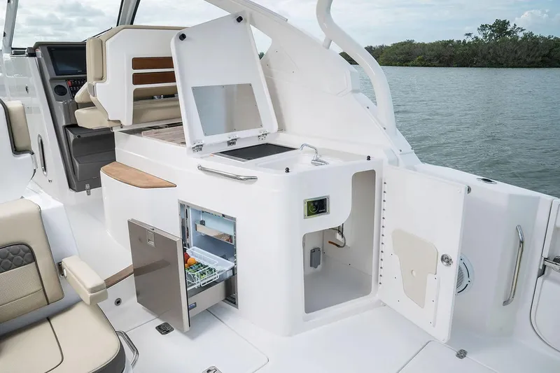 Slide: The Image of Manufacturer Provided Image: 2025 Pursuit DC 365 Dual Console boat interior with open fridge and seating area. - 16