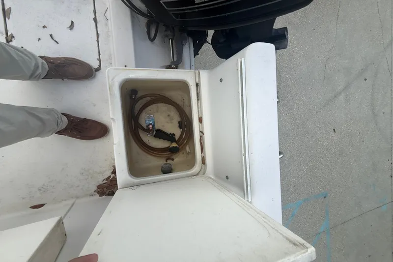 Slide: The Image of Open storage compartment on 1995 PROLINE 211 boat with hose and bottle inside. - 18