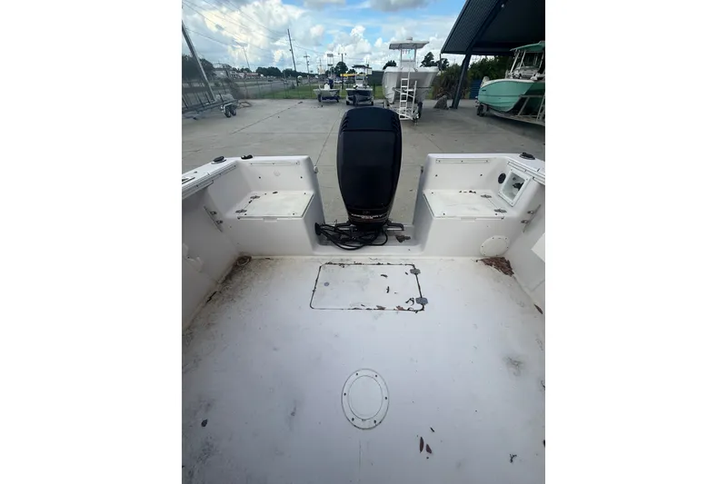 Slide: The Image of 1995 PROLINE 211 boat interior with motor, docked outdoors under cloudy sky. - 16