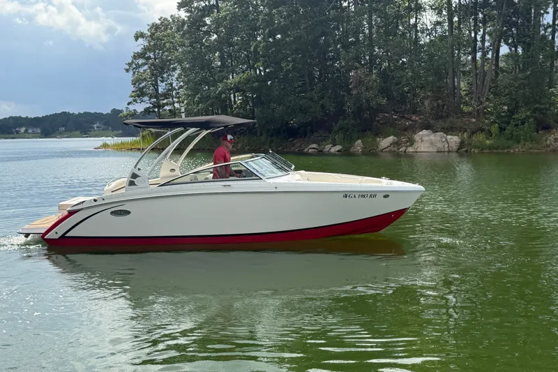 Slide: The Image of 2019 Cobalt R5 boat cruising on a serene lake near a wooded shoreline. - 1