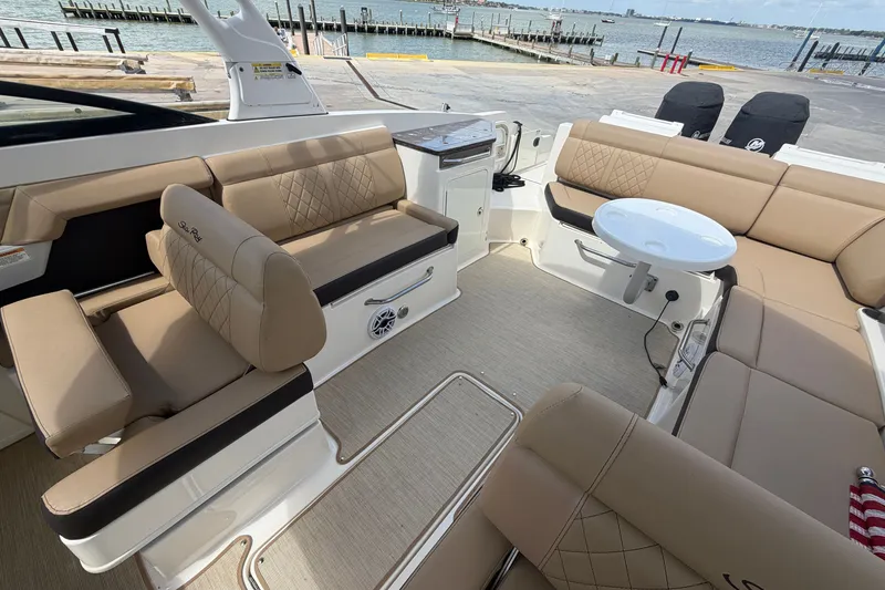 Slide: The Image of 2016 Sea Ray 290 Sundeck Outboard interior with beige seating and round table. - 6