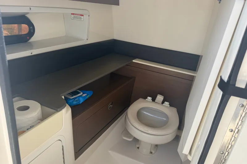 Slide: The Image of 2016 Sea Ray 290 Sundeck Outboard boat bathroom with toilet and storage shelves. - 13