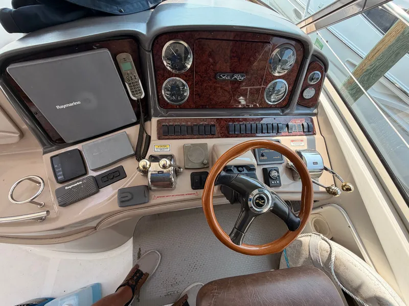 Slide: The Image of The image shows the helm of a 2004 Sea Ray 420 Sundancer with a wood steering wheel and instruments. - 20