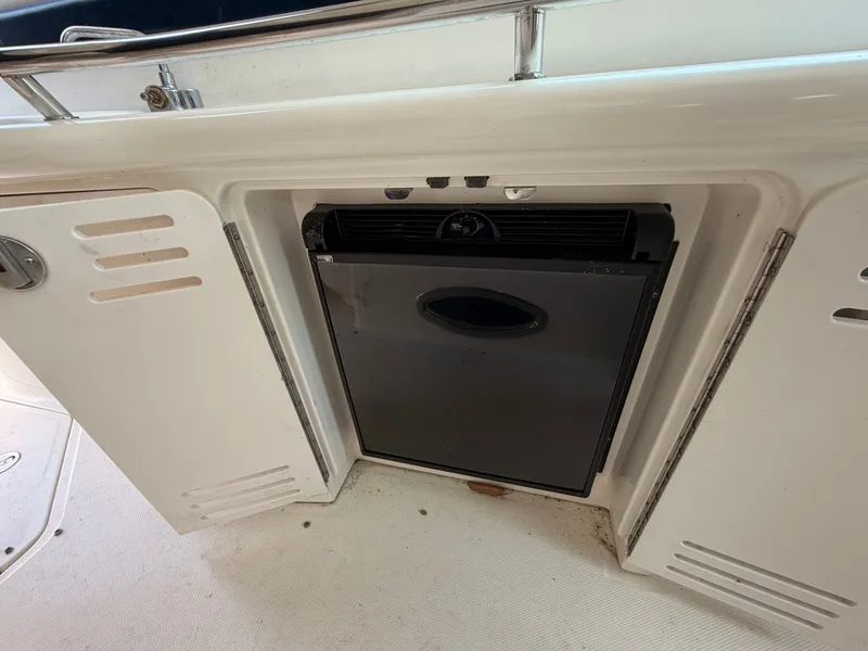 Slide: The Image of A small refrigerator is built into a white boat panel, surrounded by cabinet doors. - 47