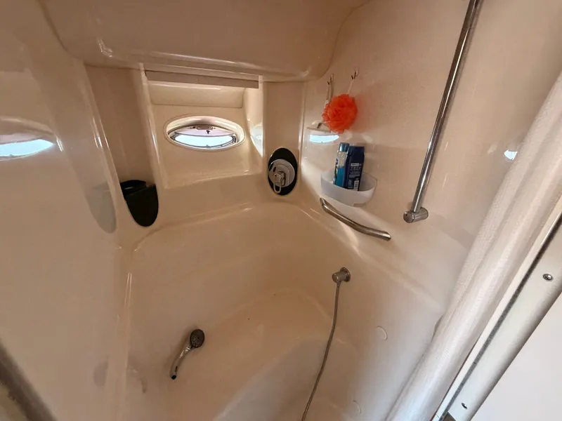 Slide: The Image of The image shows a boat bathroom with a shower, handheld showerhead, and small shelves. - 41