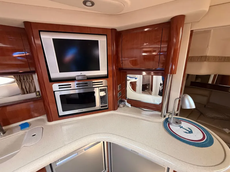 Slide: The Image of The interior of a 2004 Sea Ray 420 Sundancer features a well-equipped galley with a microwave and TV. - 31