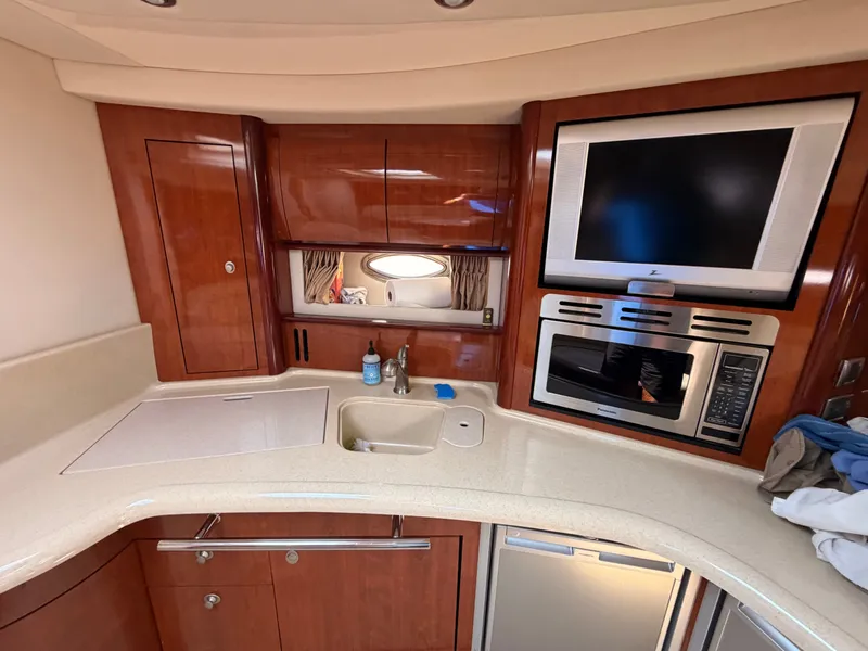 Slide: The Image of The galley of a 2004 Sea Ray 420 Sundancer with wood cabinets, sink, stove, and microwave. - 29