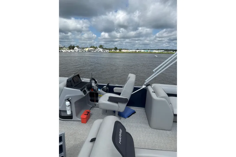 Slide: The Image of 2024 Harris Cruiser 230 boat interior with steering wheel, seats, and water view. - 7