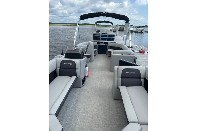 Slide: The Image of 2024 Harris Cruiser 230 pontoon boat with spacious seating on a calm lake. - 4
