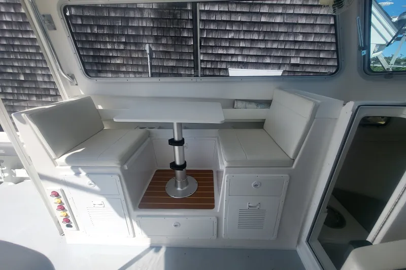 Slide: The Image of Interior seating area of 2020 Steiger Craft 28 Miami boat with table and cushioned benches. - 14