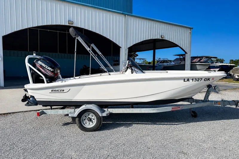 Slide: The Image of 2019 Boston Whaler 160 Super Sport boat on trailer, parked outside a metal building. - 1