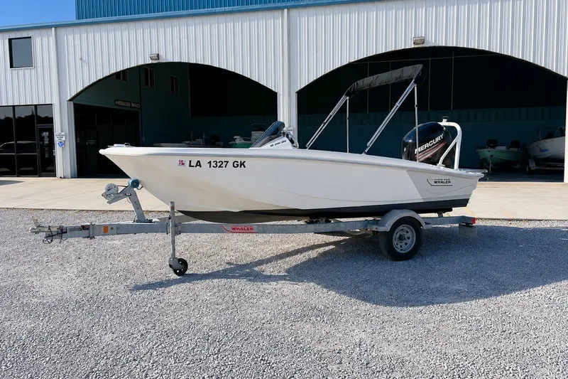 Slide: The Image of 2019 Boston Whaler 160 Super Sport boat on trailer outside a blue building. - 2