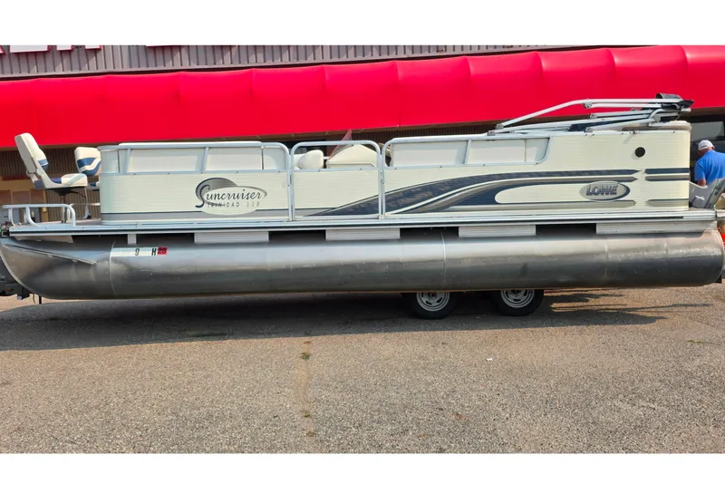 The Image of 2000 Lowe Suncruiser Trinidad 220 pontoon boat on trailer, parked outdoors. - 0
