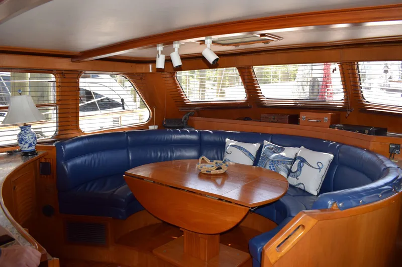 Slide: The Image of Luxurious interior of 1980 Cheoy Lee 52 Motorsailer with blue leather seating and wooden table. - 54