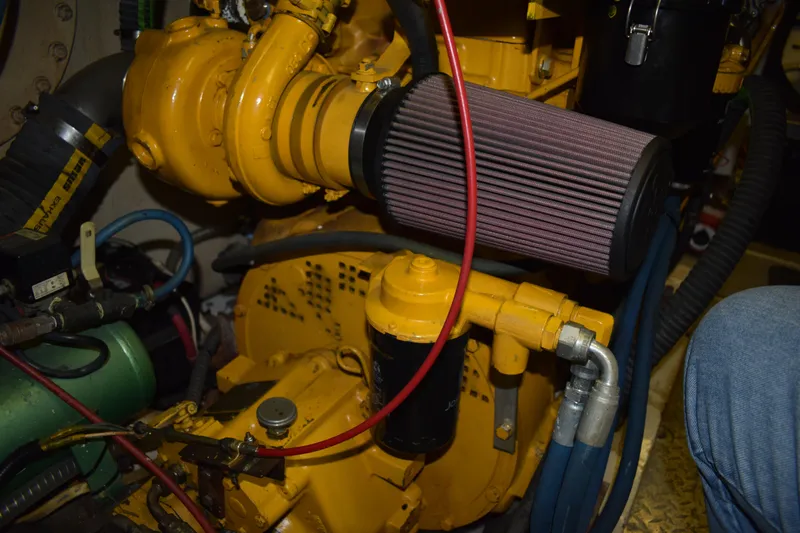 Slide: The Image of Engine compartment of a 1980 Cheoy Lee 52 Motorsailer, featuring yellow machinery and hoses. - 94