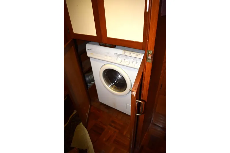 Slide: The Image of Washing machine inside 1980 Cheoy Lee 52 Motorsailer, wooden cabinetry surrounds appliance. - 64