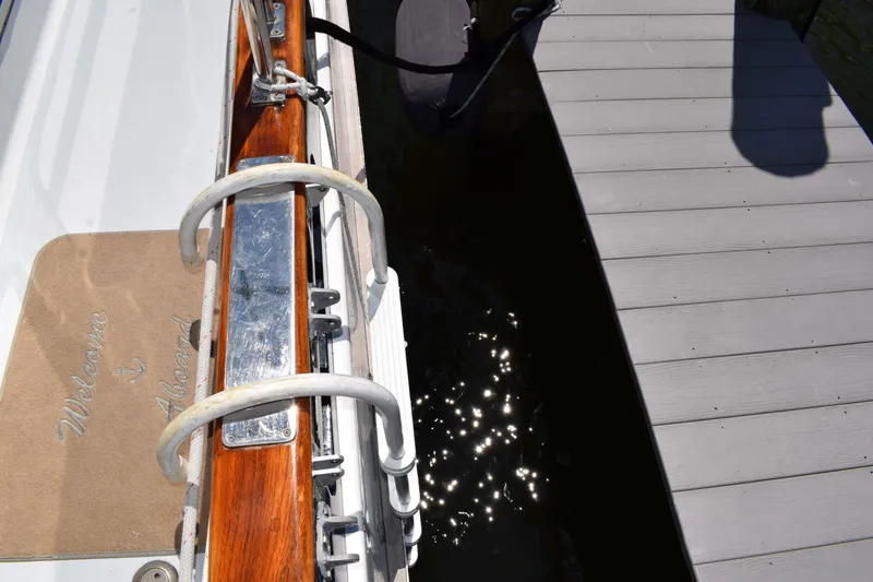 Slide: The Image of 1980 Cheoy Lee 52 Motorsailer docked, featuring a "Welcome Aboard" mat and polished wood railing. - 15