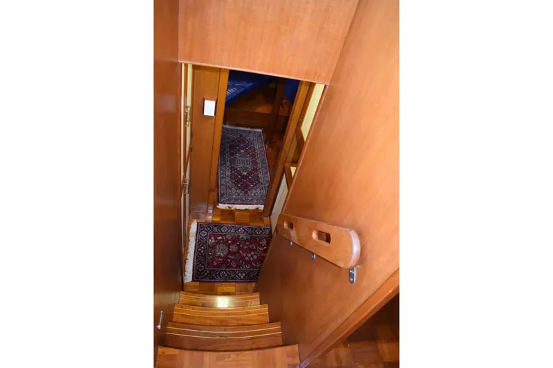 Slide: The Image of Interior staircase of 1980 Cheoy Lee 52 Motorsailer with wooden finish and decorative rugs. - 76