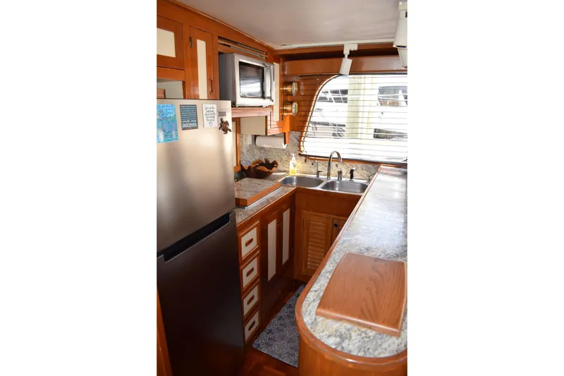 Slide: The Image of 1980 Cheoy Lee 52 Motorsailer kitchen with wood cabinetry, stainless steel appliances, and dual sinks. - 60
