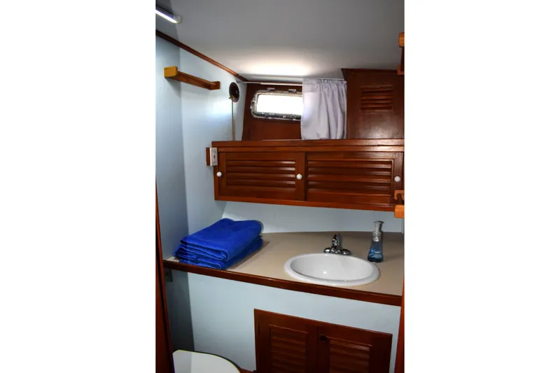 Slide: The Image of 1980 Cheoy Lee 52 Motorsailer bathroom with wooden cabinets, sink, and blue towels. - 89