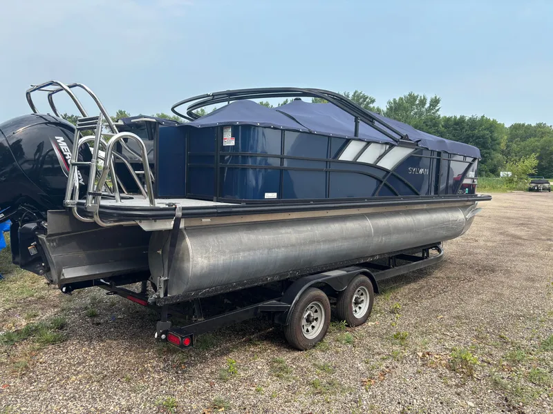 Slide: The Image of A 2021 Sylvan L3PF TRITOON on a trailer, featuring a blue cover and outboard motor. - 14