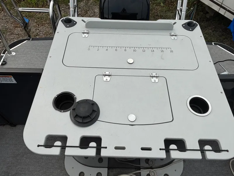 Slide: The Image of A gray table on a Sylvan L3PF TRITOON boat with cup holders and a measuring scale. - 5