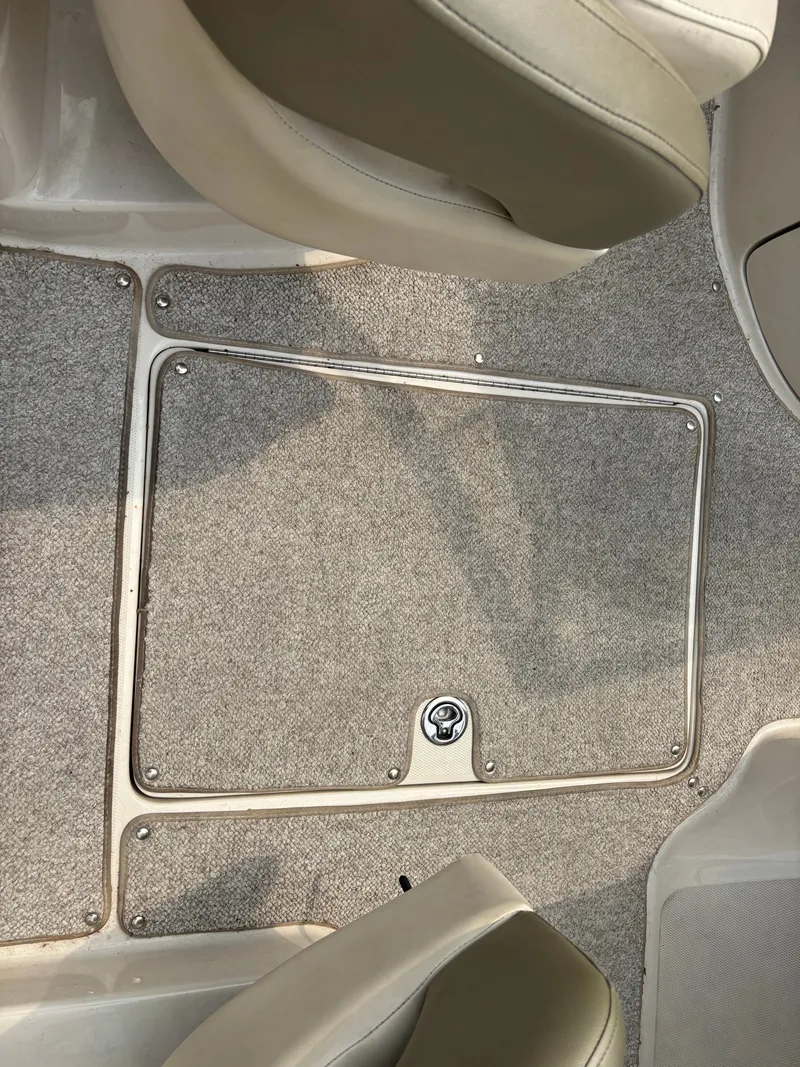 Slide: The Image of The floor of a 2005 Sea Ray 240 Sundeck with carpet and an access hatch. - 14