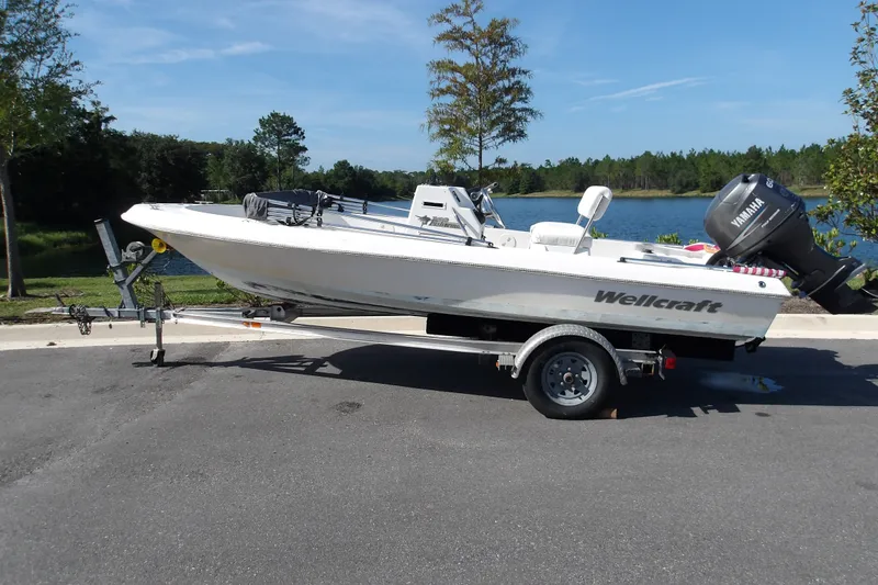 The Image of 2002 Wellcraft 160 Fisherman boat on trailer by a scenic lake. - 0