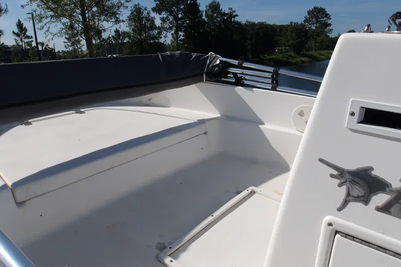 Slide: The Image of 2002 Wellcraft 160 Fisherman boat interior with seating and storage, surrounded by trees and water. - 11