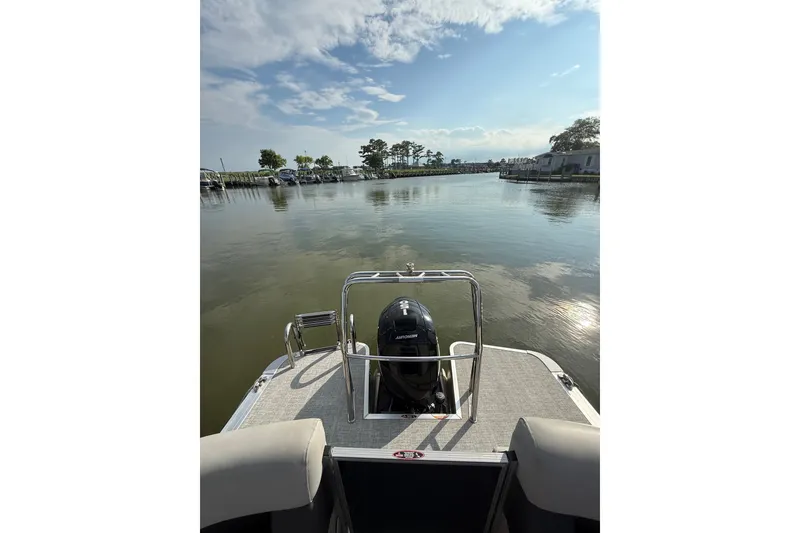 Slide: The Image of 2024 Harris Cruiser 230 pontoon boat on calm water under a partly cloudy sky. - 14