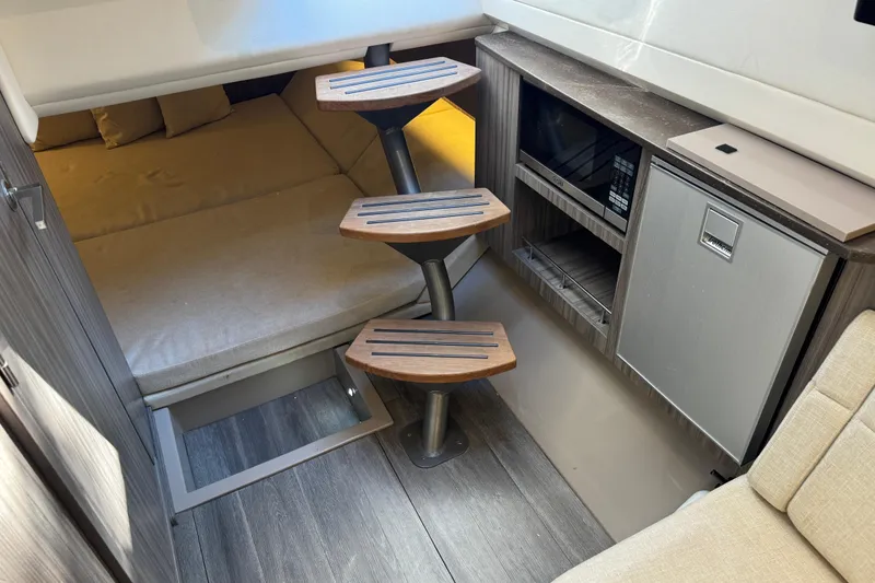 Slide: The Image of Interior of 2022 Sea Ray SLX 400 Outboard with wooden steps, bed, and kitchenette. - 74