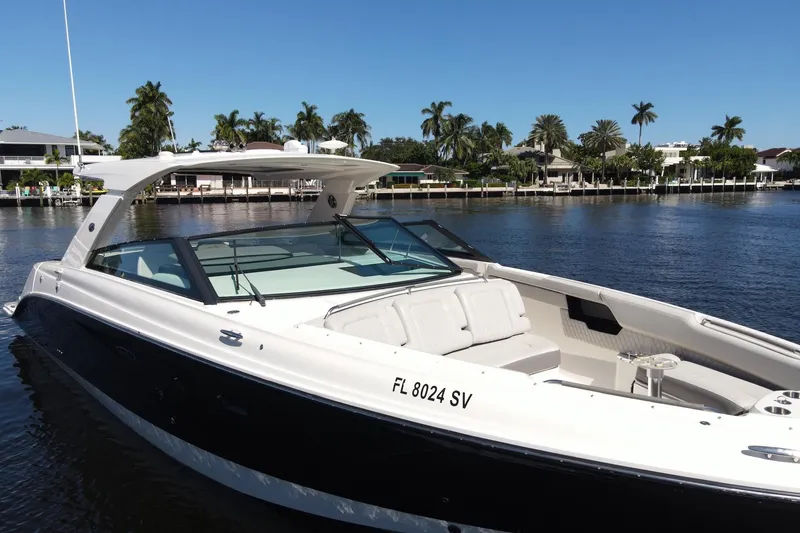 Slide: The Image of 2022 Sea Ray SLX 400 Outboard boat on a sunny waterfront with palm trees. - 1