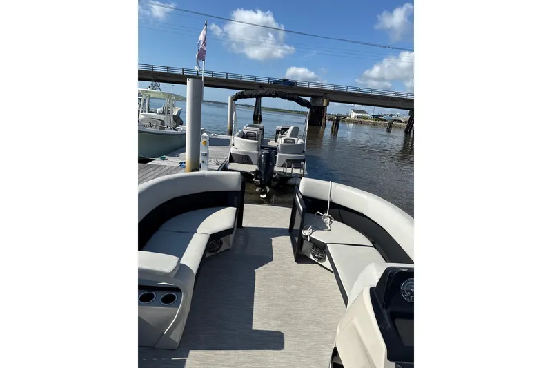 Slide: The Image of 2024 Harris Breeze 230 pontoon boat docked by a scenic bridge. - 7