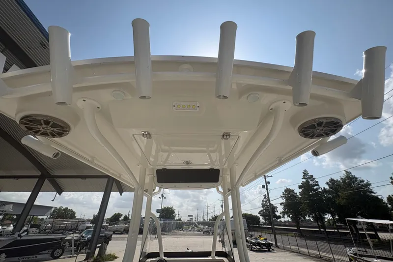 Slide: The Image of 2022 Ranger 2510 Bay boat's T-top with rod holders and speakers under sunny sky. - 22