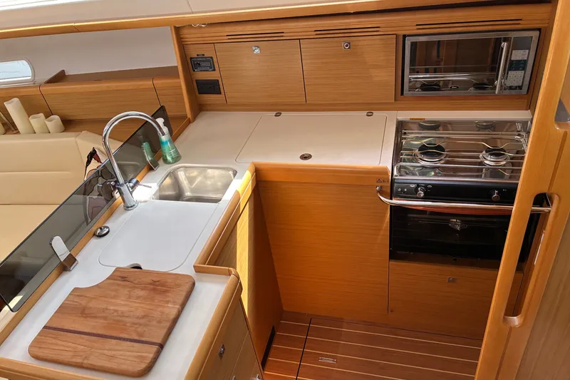 Slide: The Image of Modern kitchen in 2010 Jeanneau Sun Odyssey 42 DS yacht with stove, sink, and wooden cabinetry. - 5
