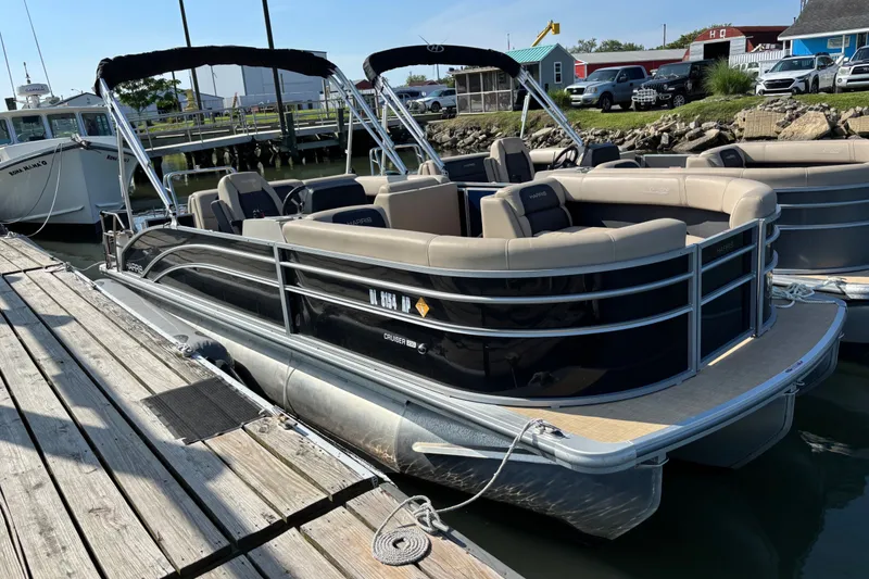 The Image of 2024 Harris Cruiser 230 pontoon boat docked at a marina, featuring sleek design and comfortable seating. - 1