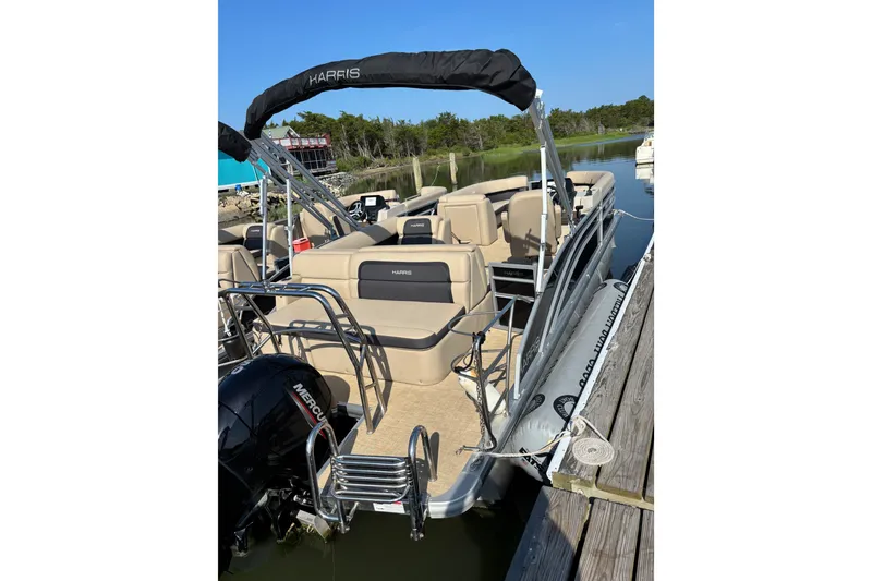 Slide: The Image of 2024 Harris Cruiser 230 pontoon boat docked, featuring comfortable seating and a Mercury outboard motor. - 4
