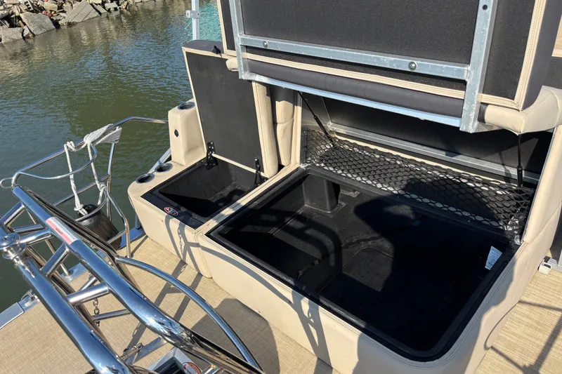 Slide: The Image of 2024 Harris Cruiser 230 boat storage compartments open by the water. - 5