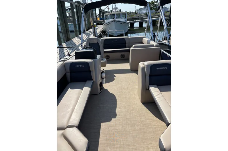 Slide: The Image of 2024 Harris Cruiser 230 pontoon boat interior with beige seating and dock view. - 3