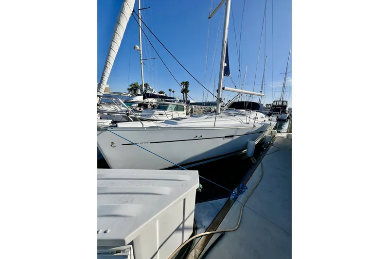 Slide: The Image of A 2006 Beneteau 393 docked in a sunny marina, surrounded by other sailboats. - 3