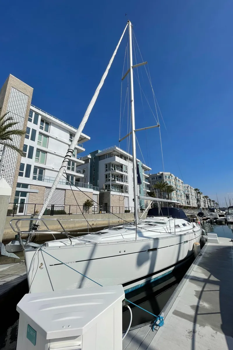 Slide: The Image of 2006 Beneteau 393 sailboat docked at a marina with modern buildings in the background. - 7