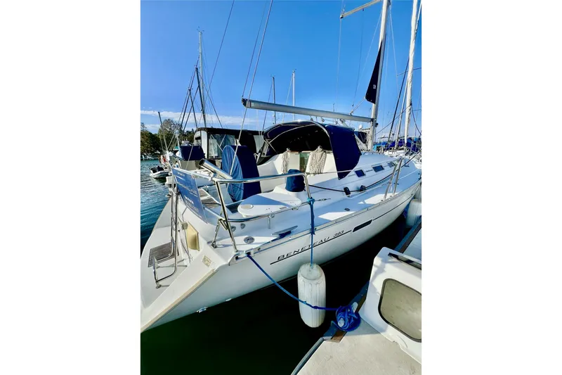 Slide: The Image of A 2006 Beneteau 393 docked in a marina. It features a white deck and blue covers. - 2