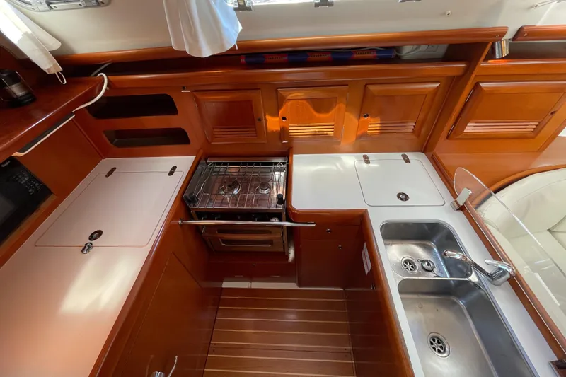 Slide: The Image of 2006 Beneteau 393 yacht kitchen with stove, sink, and wooden cabinetry. - 25