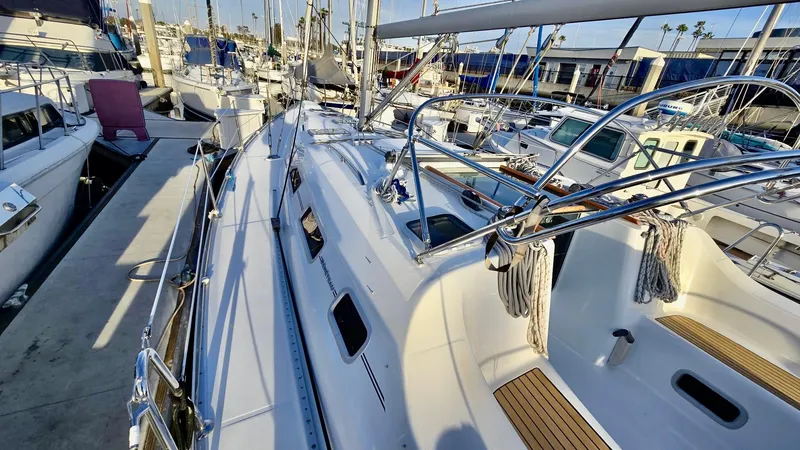 Slide: The Image of 2006 Beneteau 393 sailboat docked at marina, showcasing sleek design and spacious deck. - 17