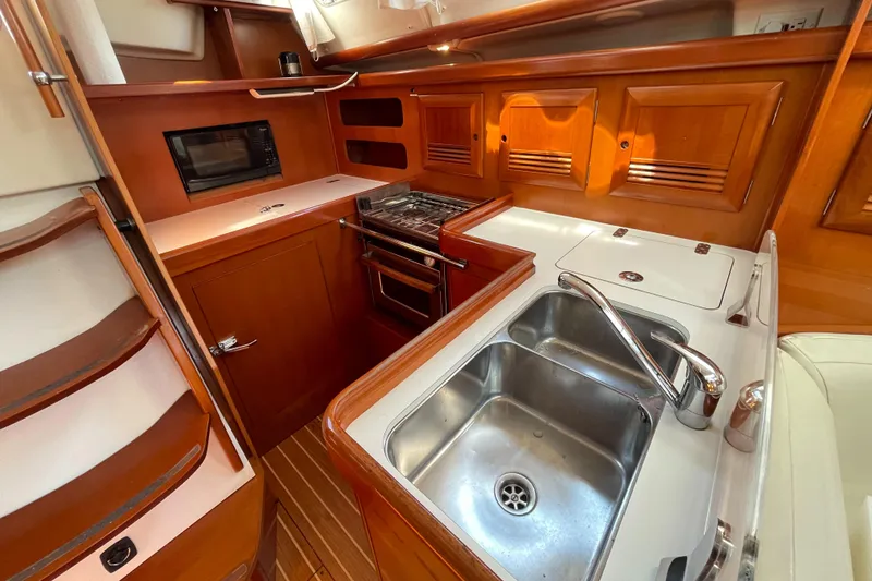 Slide: The Image of Luxurious 2006 Beneteau 393 yacht kitchen with wood cabinetry, stainless steel sink, and modern appliances. - 32