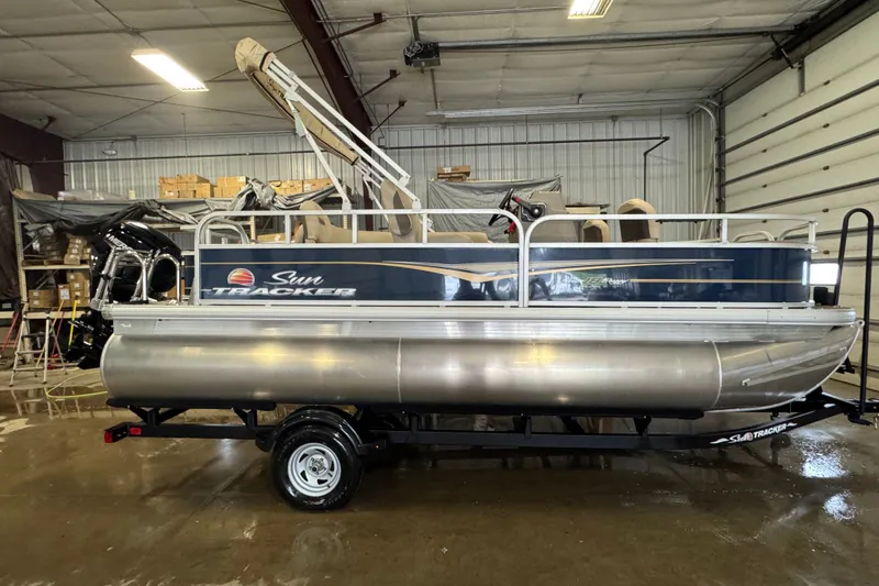 The Image of 2025 Sun Tracker Bass Buggy 18 DLX pontoon boat in a warehouse setting. - 0