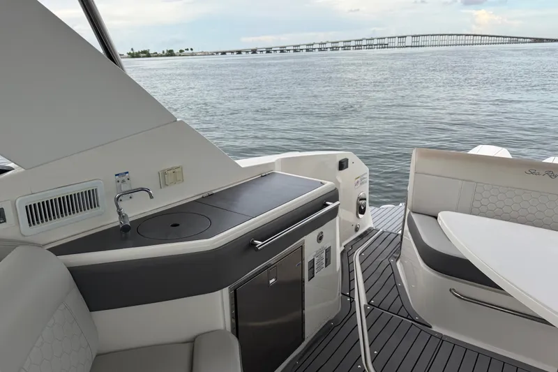 Slide: The Image of 2020 Sea Ray Sundancer 320 Coupe Outboard interior with kitchenette and seating, overlooking water. - 14
