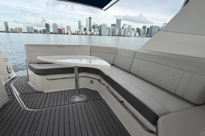 Slide: The Image of 2020 Sea Ray Sundancer 320 Coupe Outboard with city skyline view, featuring elegant seating and table. - 19