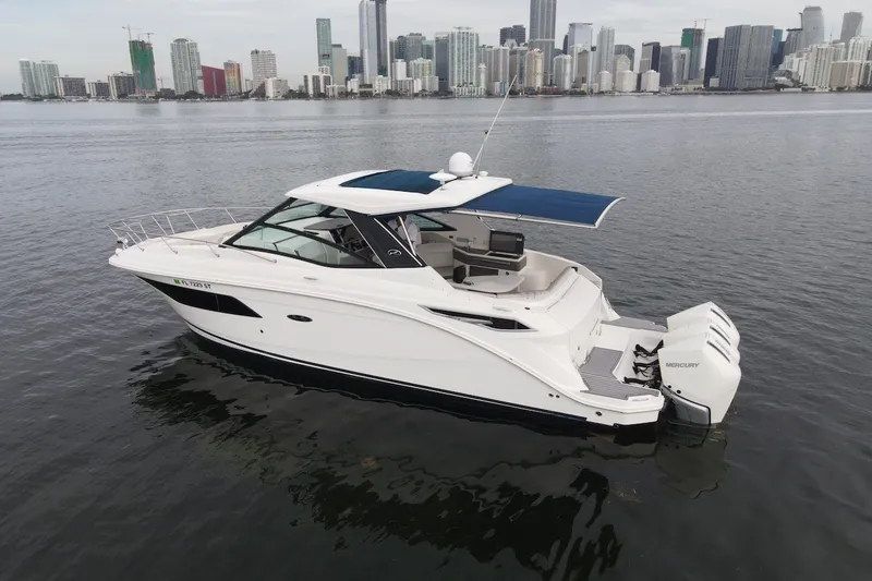 Slide: The Image of 2020 Sea Ray Sundancer 320 Coupe Outboard on water with city skyline backdrop. - 5